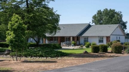 Ranch-style house in a California suburb with brick and white wood siding overlooking a large front yard.