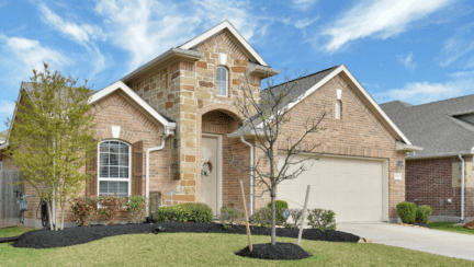 Newly-built stone exterior single-family home with a grassy front yard and an attached garage.