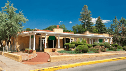 An image of a house listed for sale, with the owner looking up the cost to sell a home in New Mexico