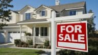 Image of a house with 'for sale' sign representing risks of scams in real estate transaction